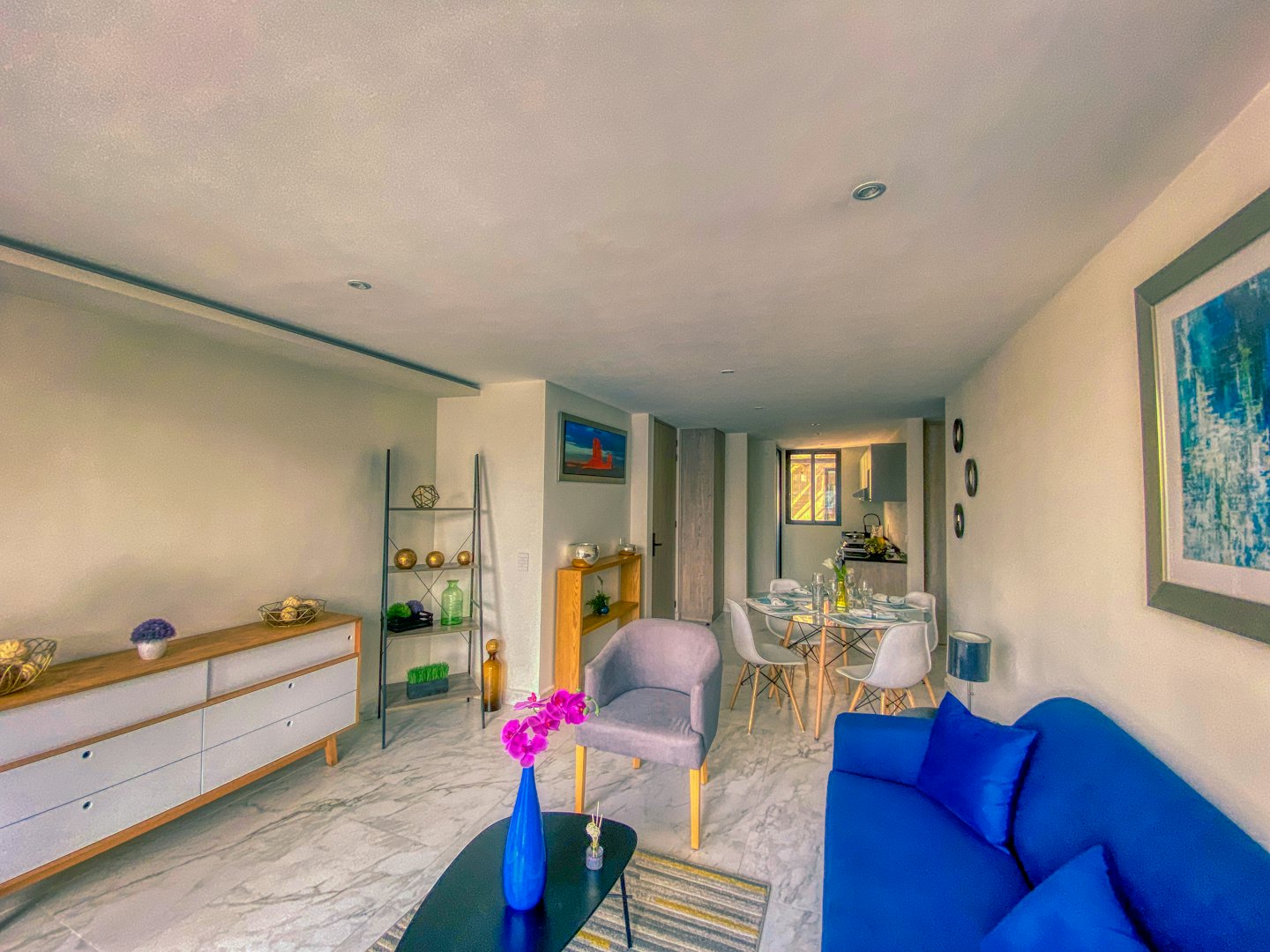 Modernes Wohn- und Esszimmer mit blauem Sofa und Orchideen.